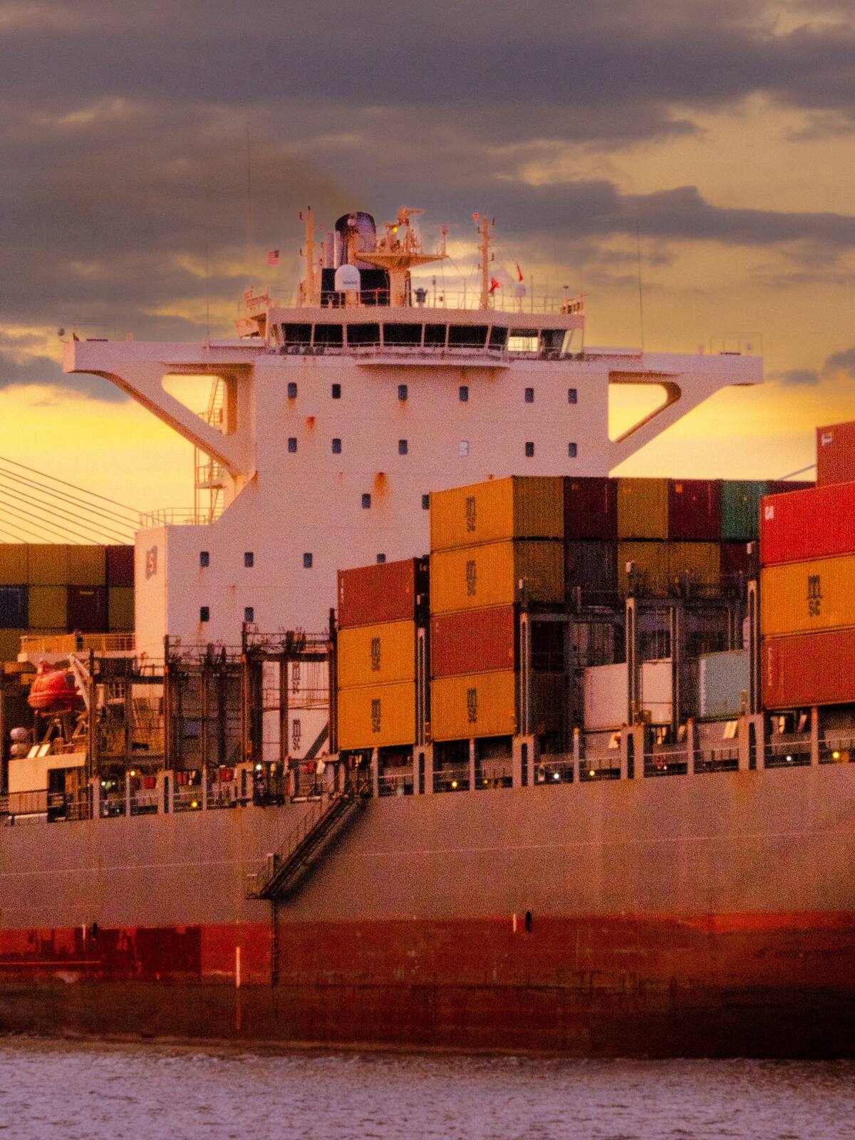 Container ship stacked with containers at sunset